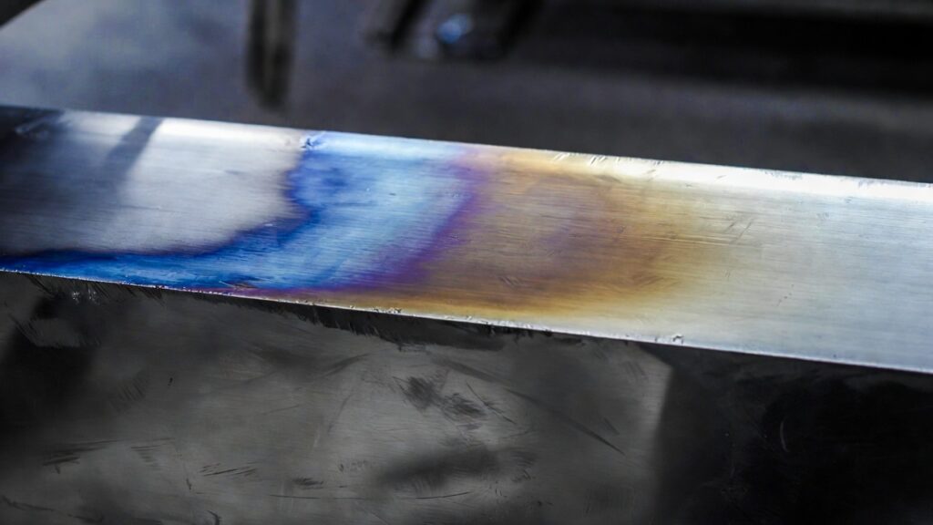 close-up of stainless steel edge with obvious blue/purple/brown heat tint and HAZ discoloration